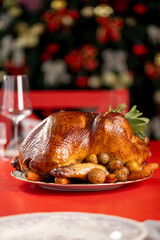A close-up of a roasted whole turkey with crispy skin, served with baby potatoes and carrots on a decorative platter in a cozy dining setting.