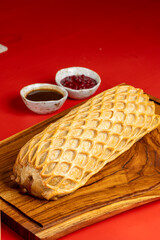 A close-up of a golden, flaky puff pastry with a delicate lattice pattern, placed on a wooden cutting board in a cozy kitchen atmosphere.