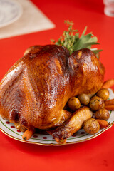 A close-up of a roasted whole turkey with crispy skin, served with baby potatoes and carrots on a decorative platter in a cozy dining setting.