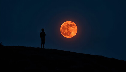 Lone figure gazing at glowing red moon on hilltop, cosmic wonder