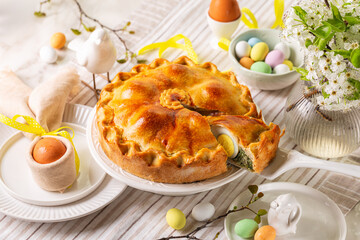 Easter table, with colored eggs, flowers, Savory Easter pie, Torta Pasqualina, made with spinach, silverbeet, leek, cheese and whole boiled eggs, originated in Italy, Liguria.  Homemade food.