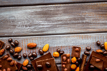 Different variety of chocolate and hazelnut on wooden background top view space for text