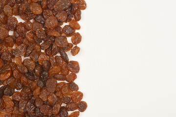 A top-down shot of a scattering of dark brown raisins on a light surface