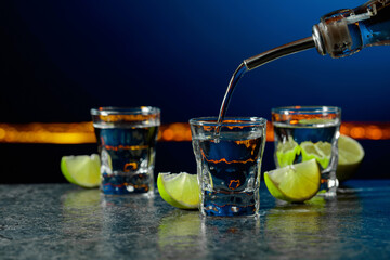 Strong alcoholic drink and lime slices on a dark blue background.