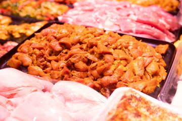 Meat department of store sells chicken meat marinated with addition of curry seasoning.