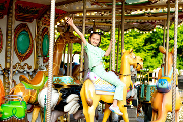 a child in an amusement park rides a carousel and enjoys the International Children's Day in...