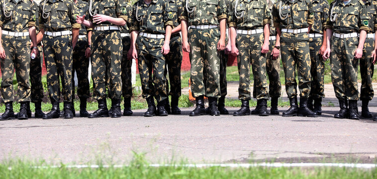 Military personnel stand in formation during a training exercise at a military base in summer