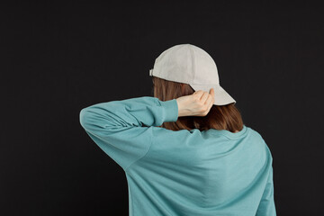 Woman in stylish baseball cap on black background, back view. Mockup for design