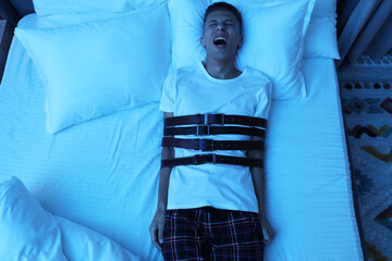 Man in sleepwalking condition screaming on bed, above view