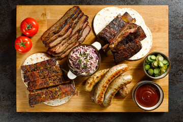 BBQ platter with smoked brisket, ribs, sausages, coleslaw, pickles, and sauce on a wooden board. Hearty, rustic, and flavorful grilled feast.
