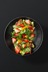 A fresh fruit and greens salad with strawberries, citrus, and avocado. Restaurant-style presentation with vibrant colors, captured under studio lighting.