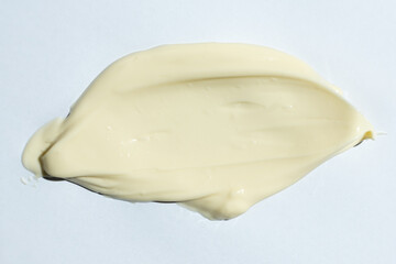 Close-up smear of mayonnaise sauce on white background, top view.