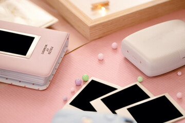 Instant photos, a camera for instant printing, and photo albums on a soft pink background,...