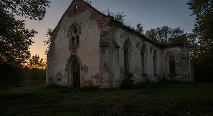 Obraz premium Crumbling abandoned church with overgrown vegetation at twilight