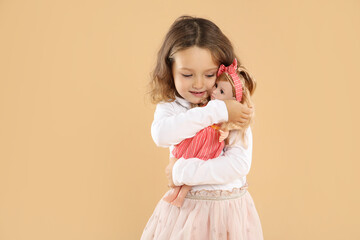 Cute little girl with doll on beige background. Space for text
