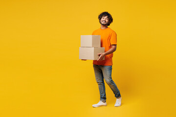 Full body young smiling fun cool happy Indian man he wear orange t-shirt casual clothes hold stack...