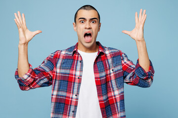 Naklejka premium Young sad stressed displeased middle eastern man he wear red shirt casual clothes spread hands cry shout scream isolated on plain pastel light blue cyan background studio portrait. Lifestyle concept.