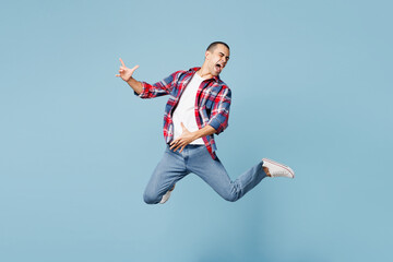 Obraz premium Full body young singer middle eastern man he wear red shirt casual clothes jump high play imaginary air guitar isolated on plain pastel light blue cyan background studio portrait. Lifestyle concept.