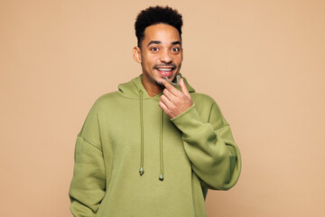 Young man of African American ethnicity wears green hoodie casual clothes hold in hand invisible...