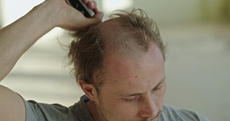 Obraz premium A man shaving his head in soft light, reflecting his dedication to grooming and style