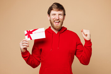 Young happy fun man he wear red hoodie casual clothes hold gift certificate coupon voucher card for...