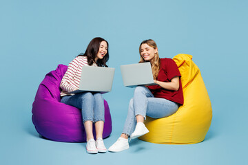Full body young couple two IT friends women wearing red casual clothes together sit in bag chair...