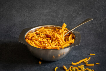 Bombay mix in a metal bowl—a popular Indian snack consisting mixture of sev, fried lentils, peanuts, and chickpeas.
