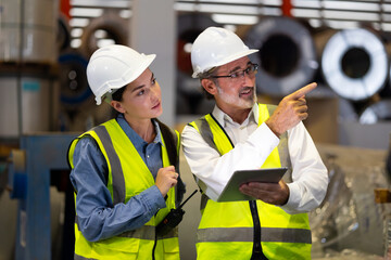 Two professional engineer worker working control sheet metal roof tile roll forming machine at metal sheet profiling factory. Industrial production. Teamwork