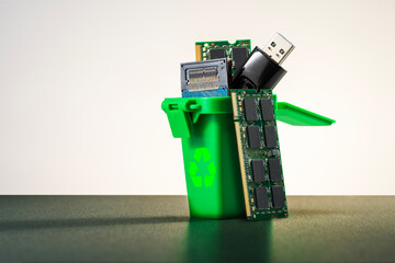 Green bin with circuit boards and electronic parts. Proper disposal of e-waste.