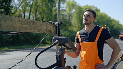 A construction worker skillfully operating heavy machinery on the road for infrastructure work