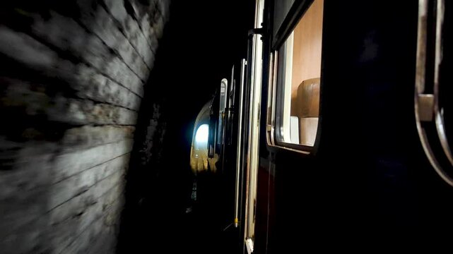 Train passing through darkness with light at end of tunnel during Sri Lankan train journey on Kandy to Ella route in highlands of Sri Lanka