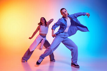 Passionate hip hop dancers executing synchronized moves in casual urban outfits under neon light...