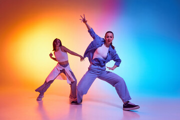 Two hip hop dancers embracing street culture with bold freestyle moves under neon gradient lighting. Concept of rhythm, urban passion, youth energy, contemporary movement, artistic expression.