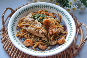A  bowl of Mee Hailam, with tender noodles, shrimp, chicken, vegetables, and a rich, aromatic broth.