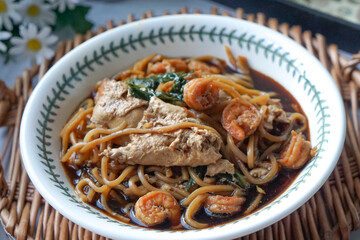 A  bowl of Mee Hailam, with tender noodles, shrimp, chicken, vegetables, and a rich, aromatic broth.
