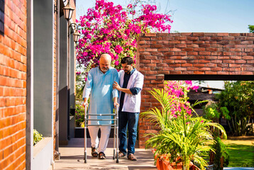 Indian senior patient walks home with a walker, assisted by a young doctor after hospital discharge