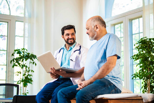 Indian doctor and senior patient discussing diagnosis on laptop in a cozy clinic setting
