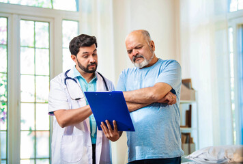 Doctor discusses diagnosis and treatment with elderly patient in an airy hospital hallway