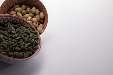 Pistachios and pumpkin seeds in decorative bowls with copy space
