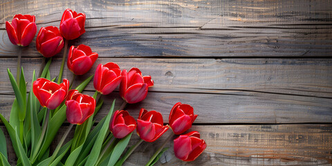 Naklejka premium Czerwone tulipany na tle drewnianej powierzchni, tworzące naturalną, wiosenną kompozycję.