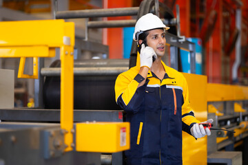 man hands using mobile phone. Hispanic man worker in safety hardhat helmet at steel factory, metal sheets and industrial machinery in a large manufacturing plant.