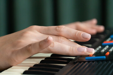 Fototapeta premium Close-up of a musician's hand adjusting the settings on a vintage synthesizer keyboard, exploring different sounds and creating electronic music