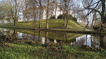 On the hill surrounded by a moat stands a large white historic castle