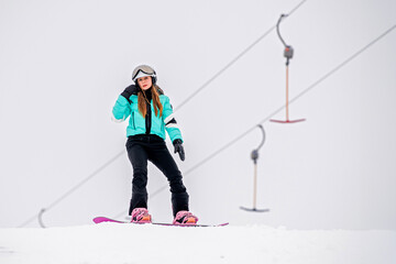 Young female snowboarder gliding down a snowy slope, dressed in stylish winter gear. Exciting...