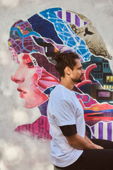 Artistic fusion man sits before vibrant mural