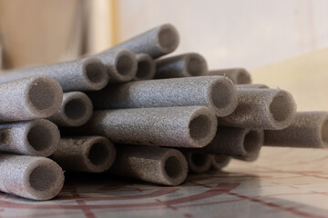 Grey soft isolation for pipes of the water supply and heating system. Closeup, selective focus.