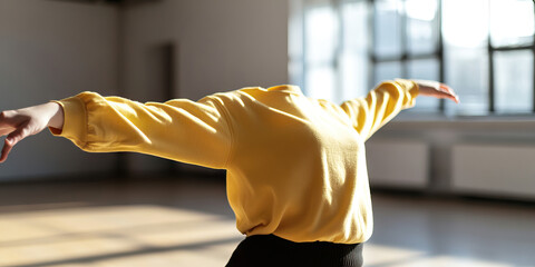 Headless Figure in Yellow Sweatshirt Performing a Stretch in a Studio