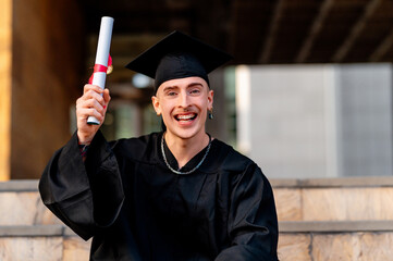 Cheerful graduate smiling brightly and proudly holding diploma on graduation day, celebrating...