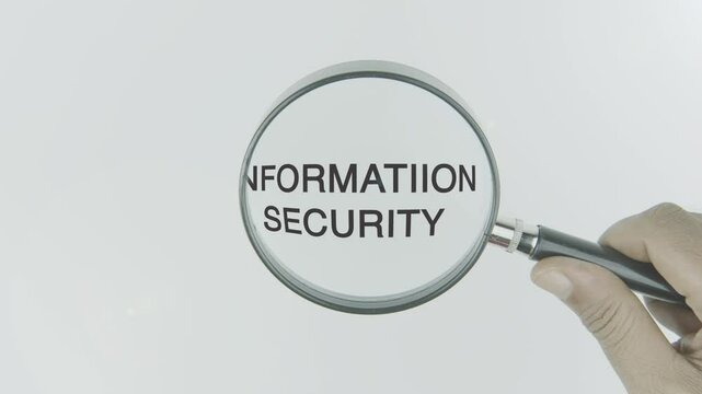 Information security text or word highlighted by a magnifying glass in a hand on a white background, symbolizing data protection, privacy, and cybersecurity measures