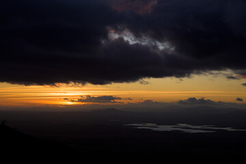 Autumn sunset light with clouds in blue sky with mountain landscape between the trees in horizontal chemtrails